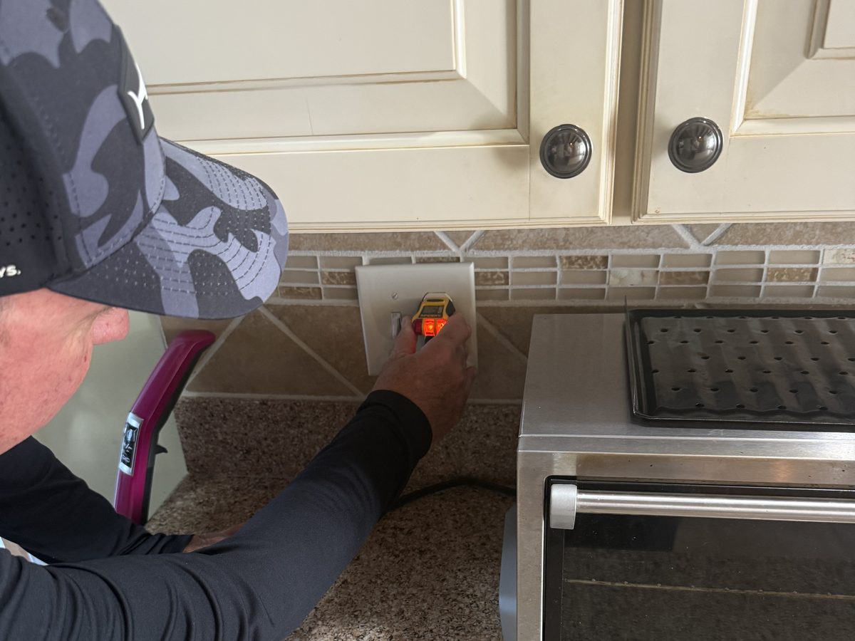 Testing a kitchen outlet during an inspection